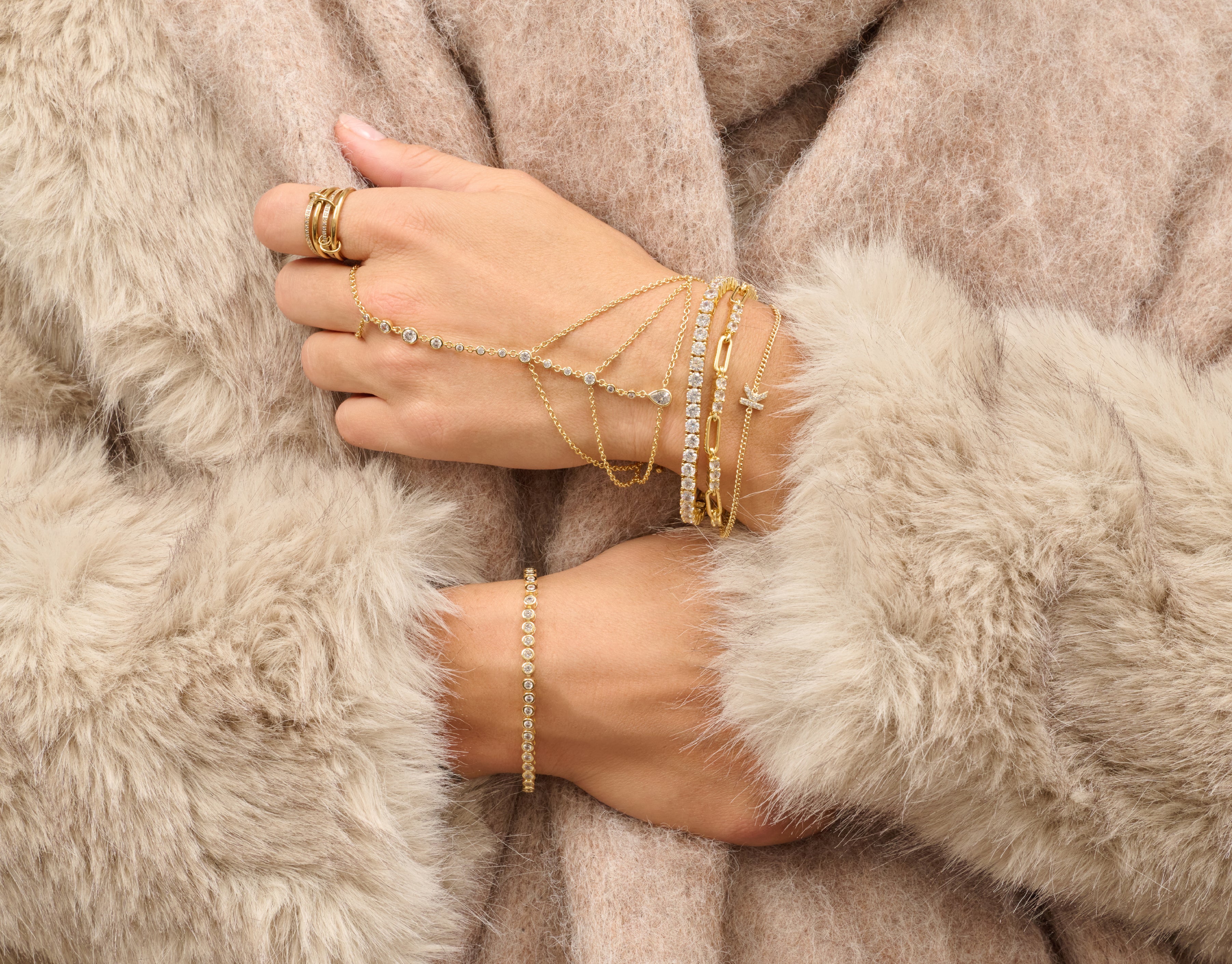 Hand wearing gold jewelry against a fur background